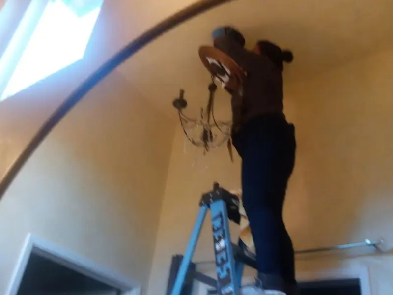 Electrician installing a chandelier in a Fletcher residence